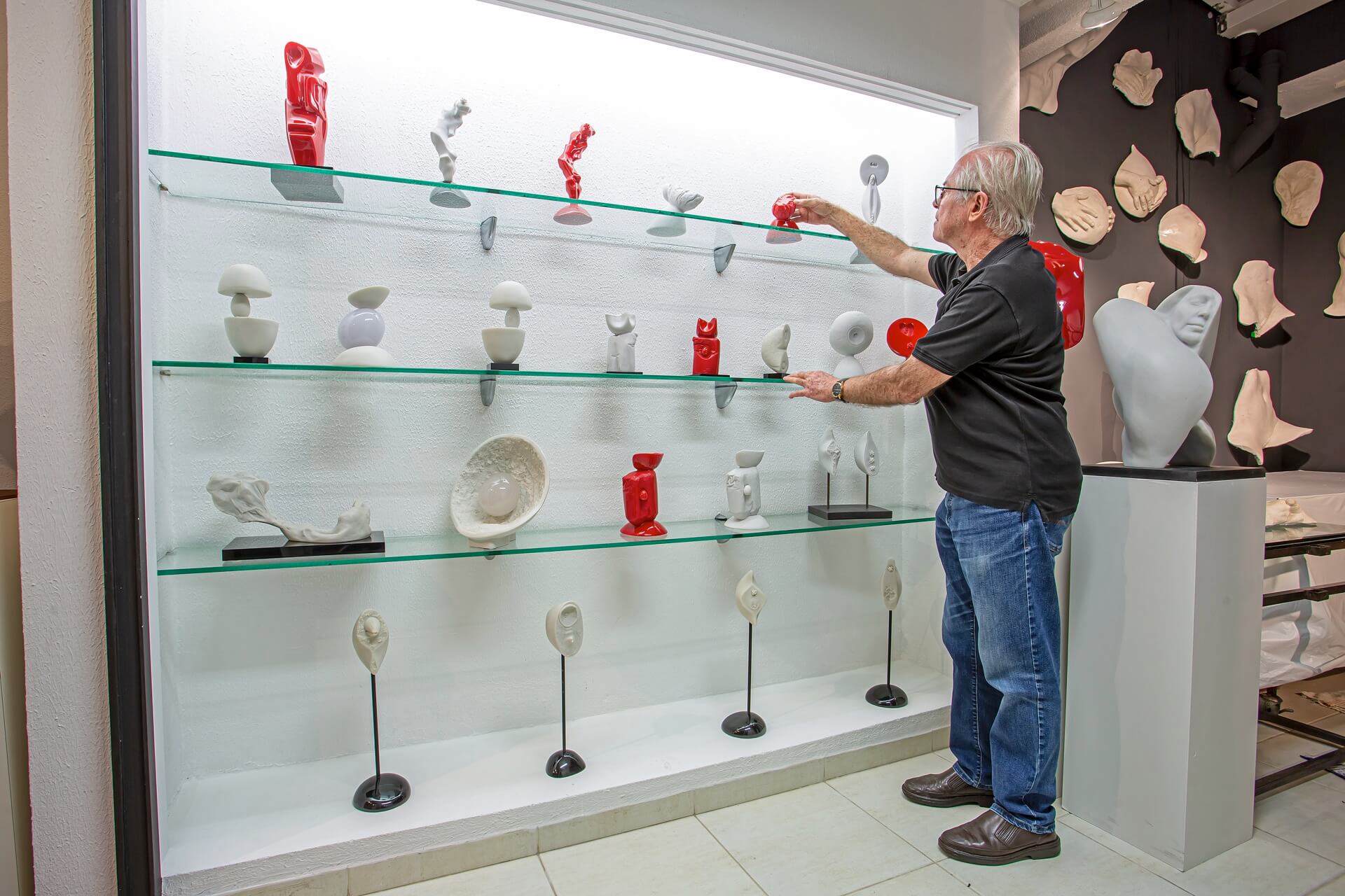 Gavira organizando esculturas nas prateleiras do ateliê
