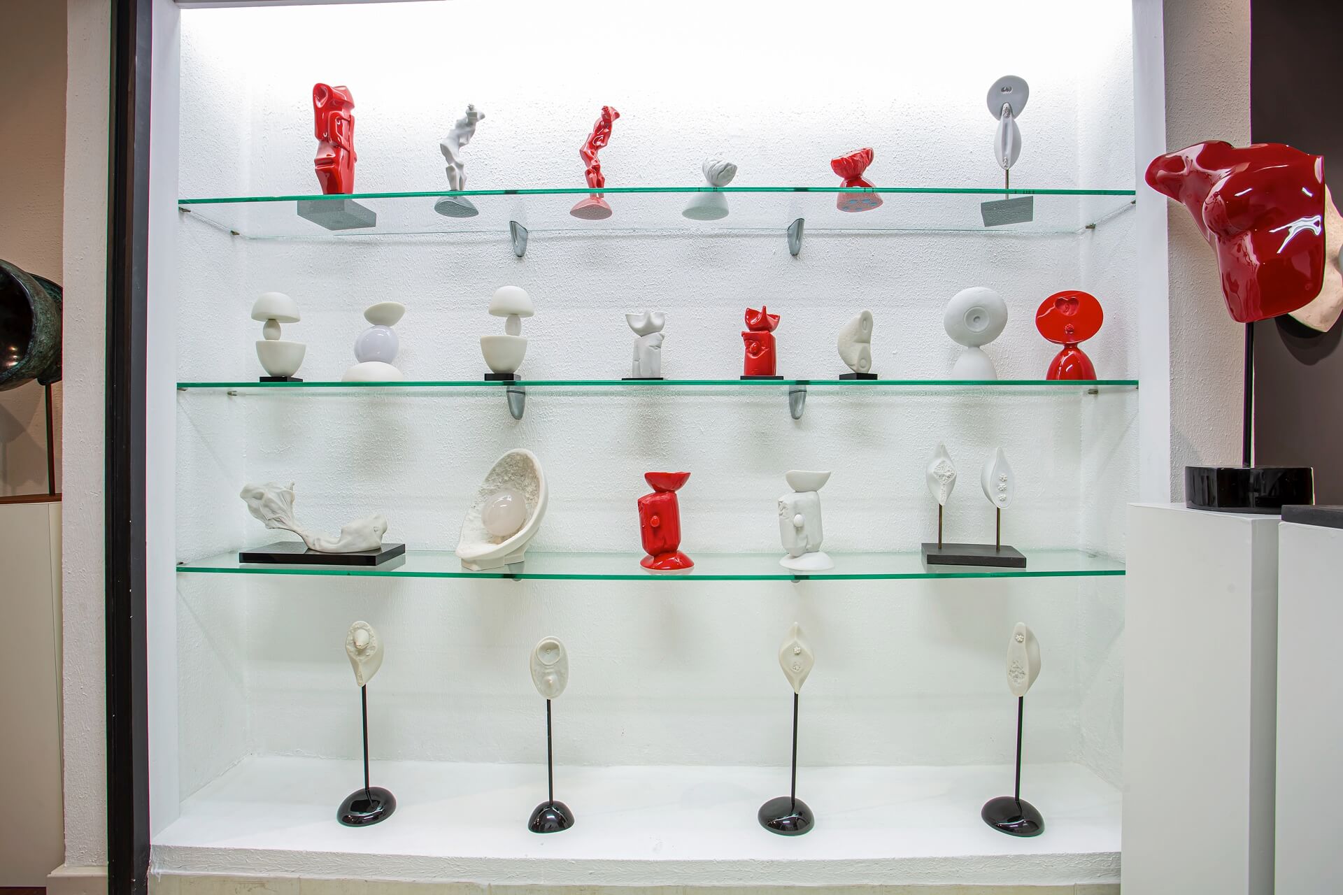 Composição de esculturas em mármore branco e resina vermelha na vitrine