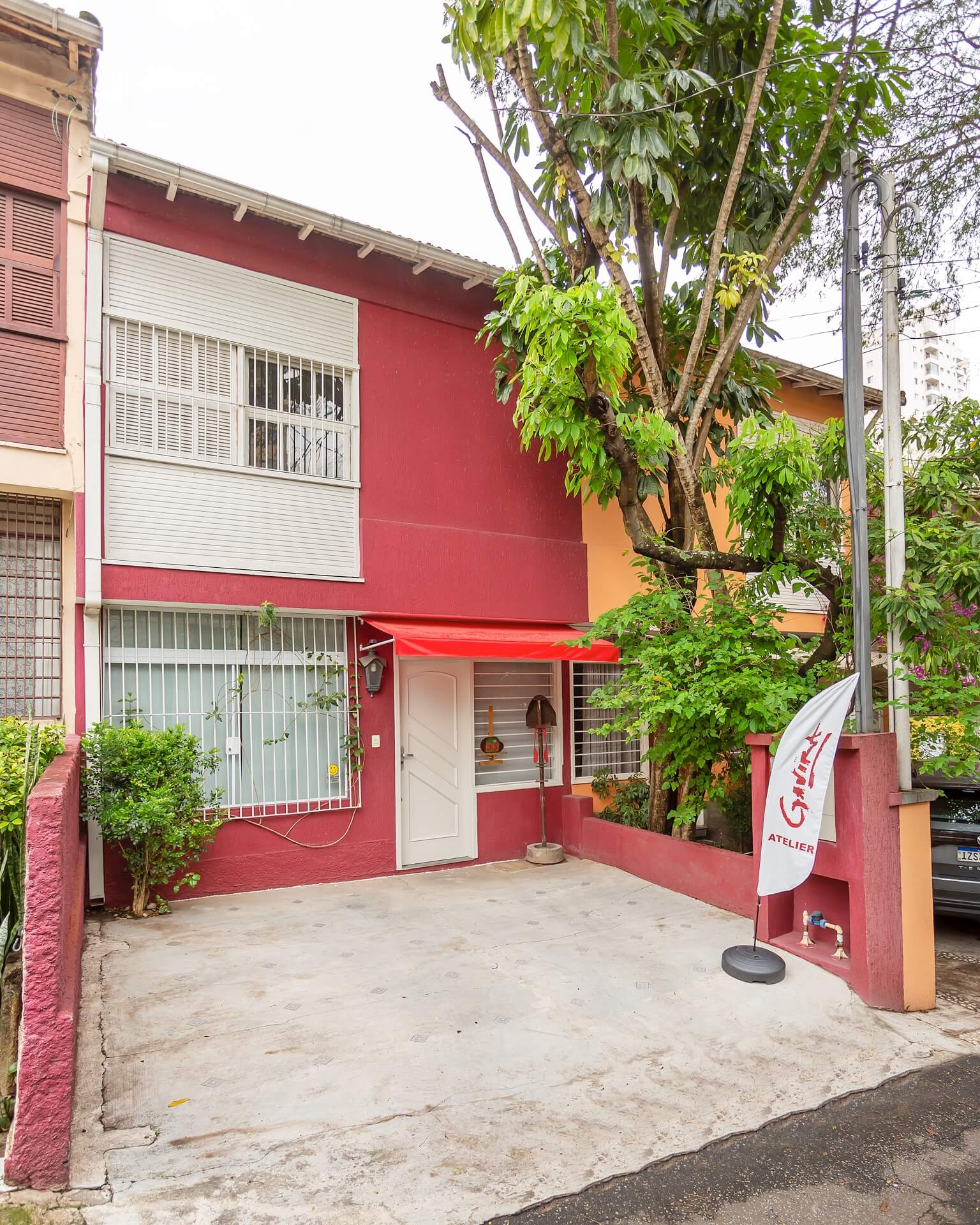 Fachada do ateliê Gavira em tom vermelho com bandeira da assinatura do artista